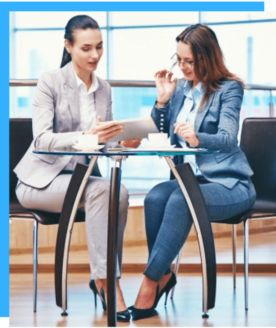 Image of two corporate females seated and working together 