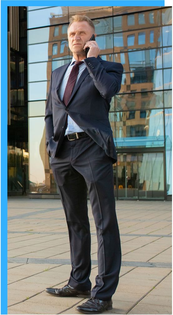 Image corporate male in a suit standing outside glass building holding cell phone to his ear